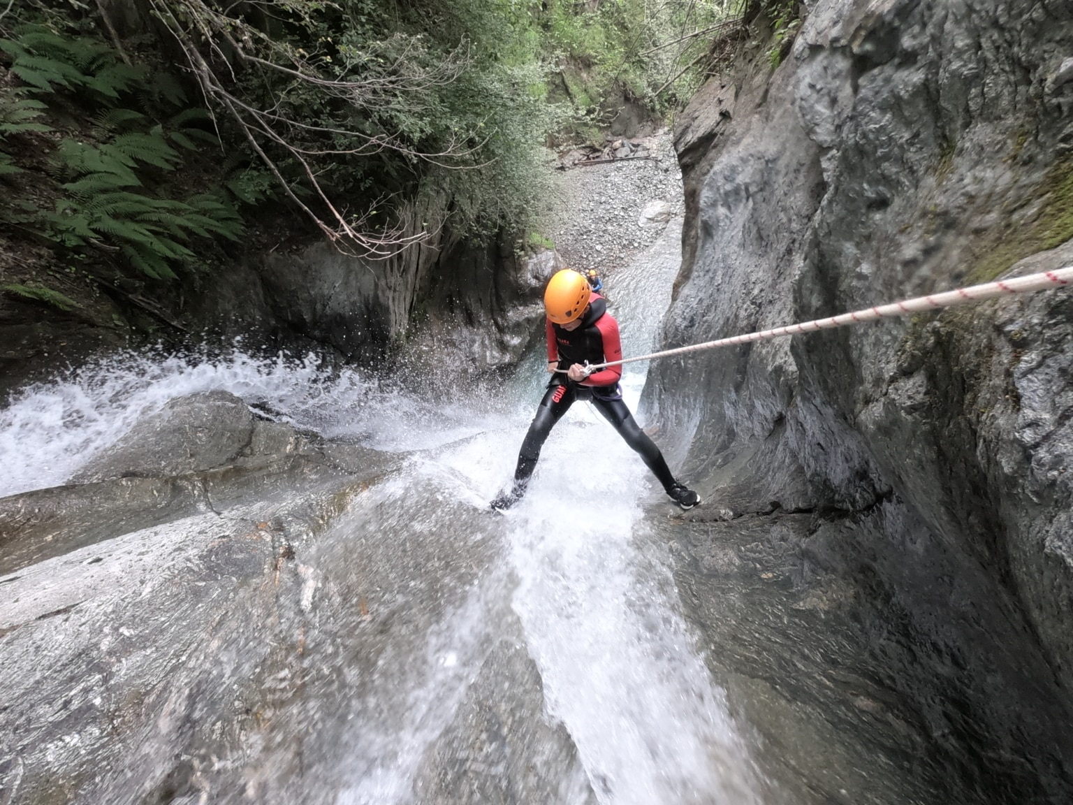 Photographie prise dans le Canyoning de Bénétant, un homme descend une cascade en rappel